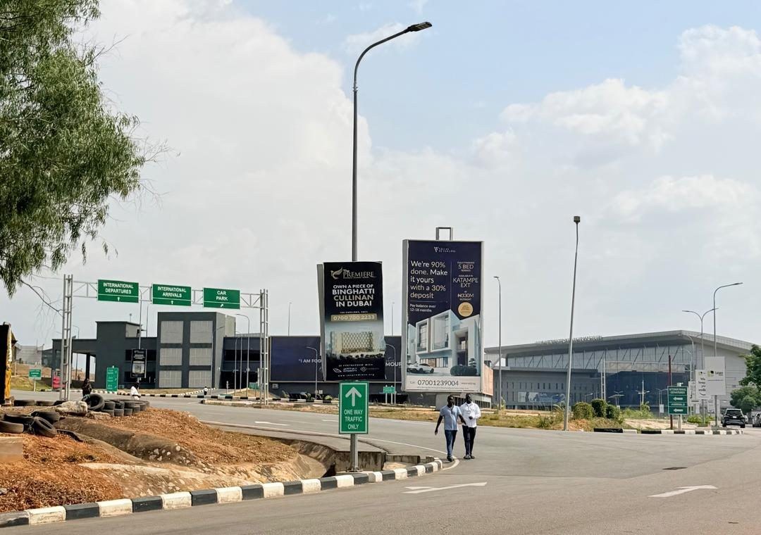 ABV-012 · Static Billboard — International Terminal Entrance, Nnamdi Azikiwe International Airport advertising face and surrounding environment