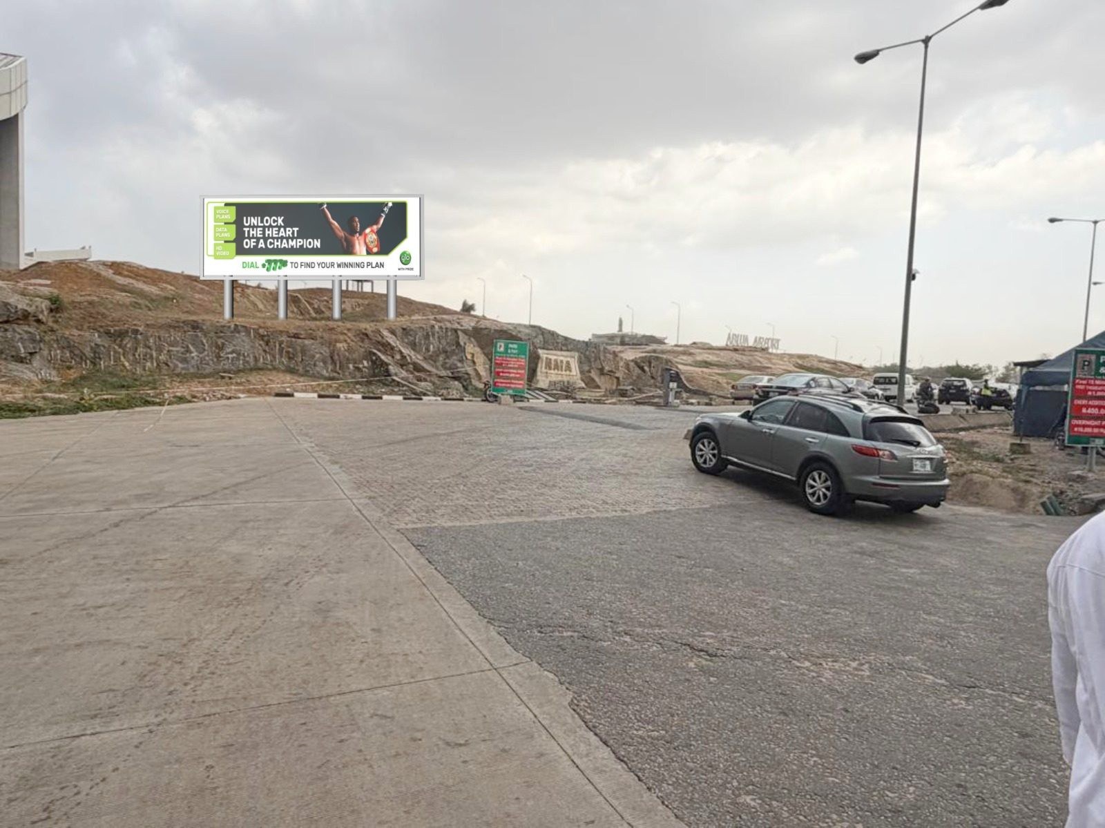 ABV-021 · Airport Billboard — Hilltop By Exit Of Domestic Car Park, Abuja Airport advertising face and surrounding environment