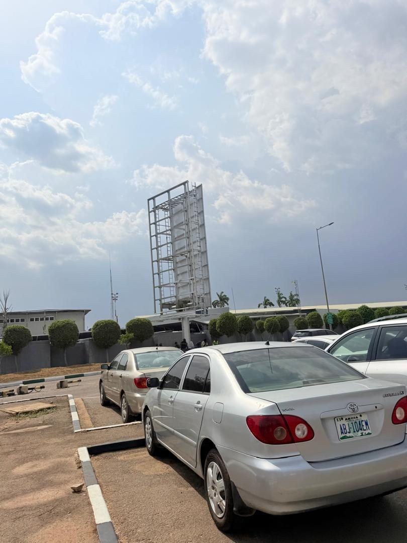 ABV-011 · Static Billboard — VIP Car Park Exit, Nnamdi Azikiwe International Airport advertising face and surrounding environment